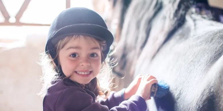 Smiling young child in a dark cap indoors with warm light