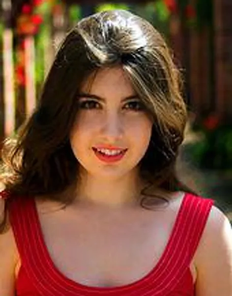 Portrait of a woman in a red sleeveless top looking toward the camera