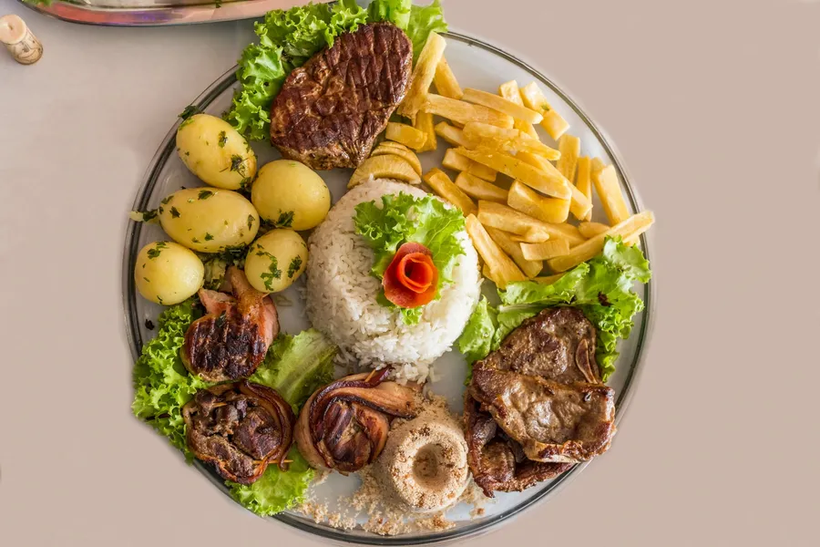 Overhead plated meal with rice, fried egg garnish, steak, fries, lettuce, potatoes, and onion rings